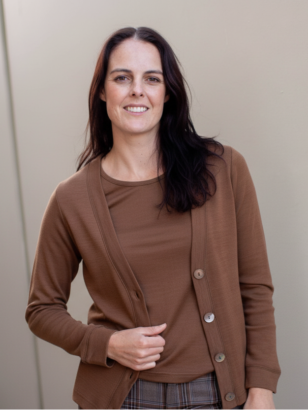 Woman wearing a brown cardigan and plaid pants against a neutral background