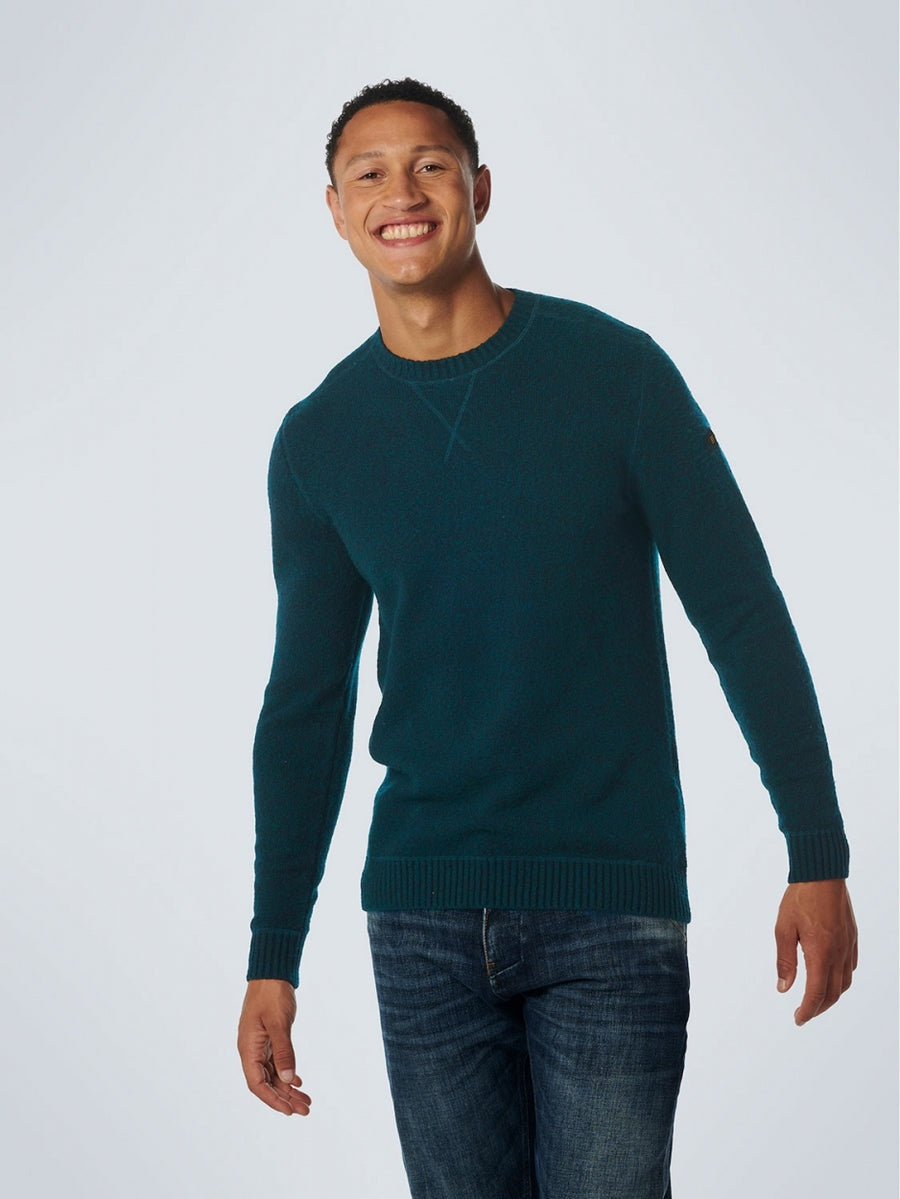 A male model wearing an ocean-colored, long-sleeved, soft stretch crewneck pullover with ribbed detailing on the hem, cuffs, and collar.