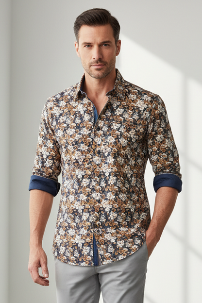 A folded long-sleeve button-up shirt with a dense floral print in brown, beige, and white over a navy blue base, featuring a solid navy collar and a visible 'English Laundry' neck label, laid flat on a wooden surface.