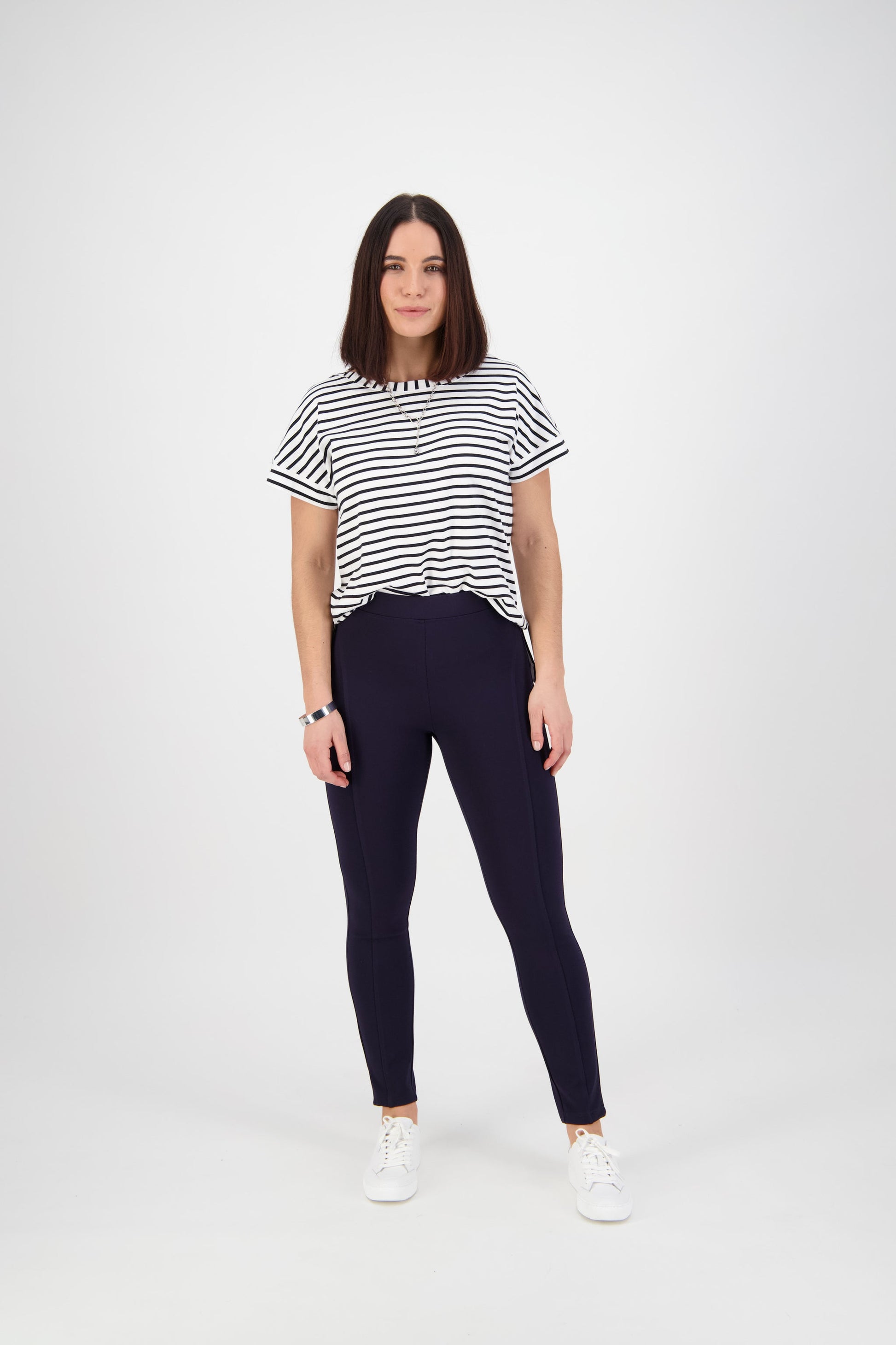 Woman wearing navy leggings with striped tee and white sneakers, casual fashion outfit