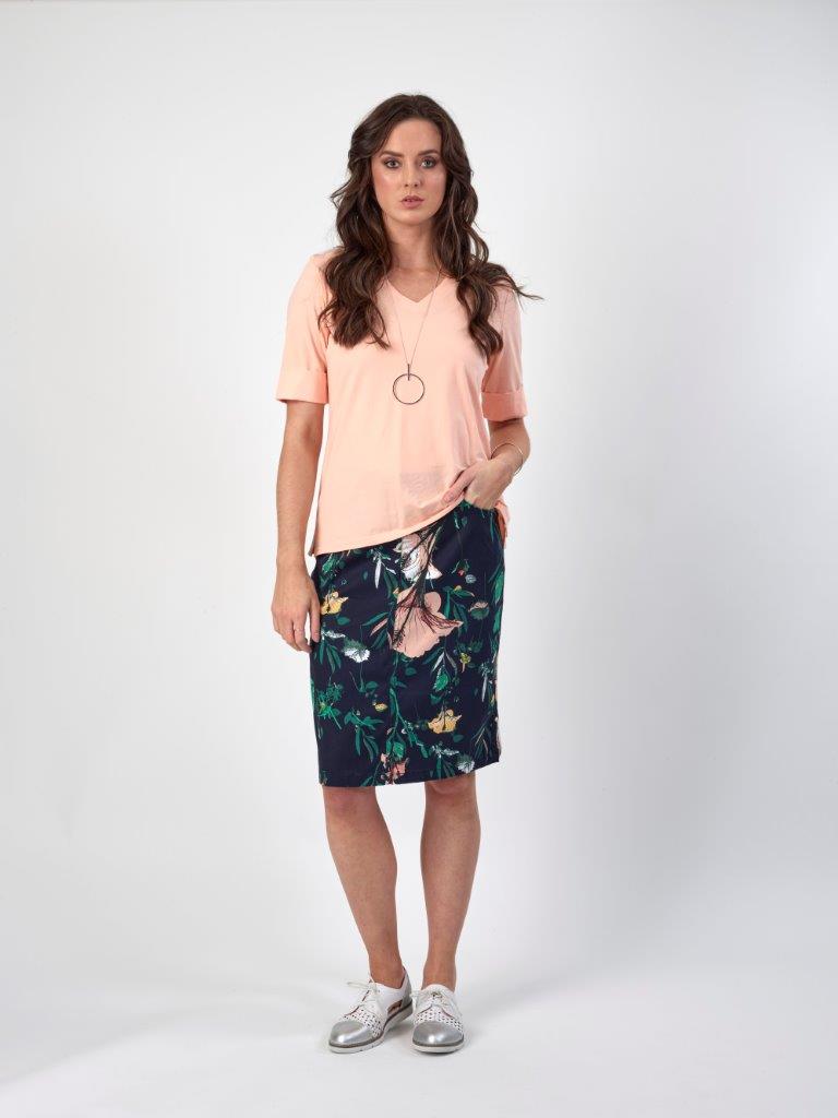 Woman in peach V-neck tee and navy floral skirt, silver sneakers, casual women's fashion outfit
