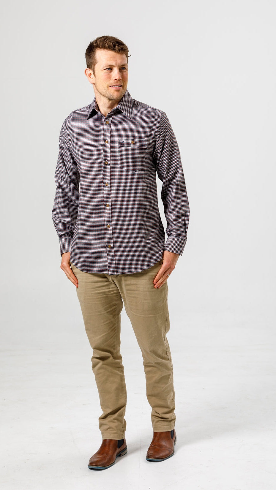 Man wearing a patterned shirt and beige pants on a white background