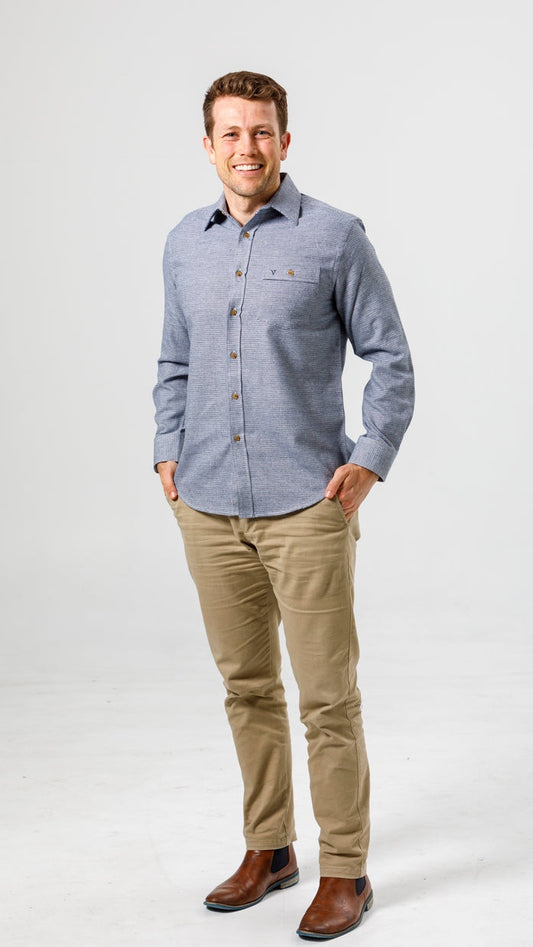 Man wearing a blue button-up shirt and beige pants on a white background