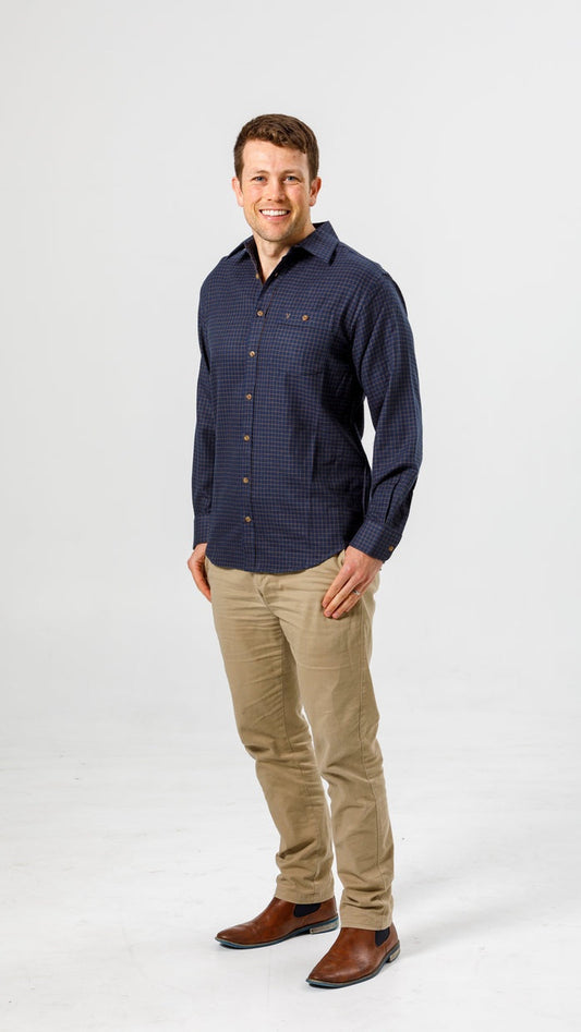 Man wearing a navy patterned shirt and beige pants on a white background