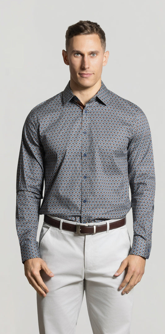 Man wearing a patterned shirt and light pants against a plain background